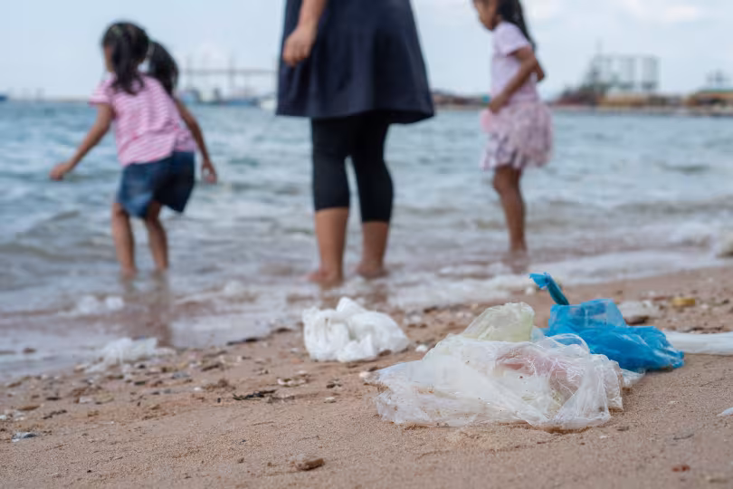 enfant se baignant sur plage avec déchets